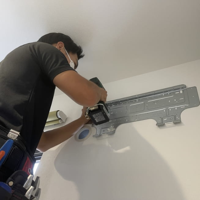 据付板を壁に固定してエアコンの取付け準備をしている